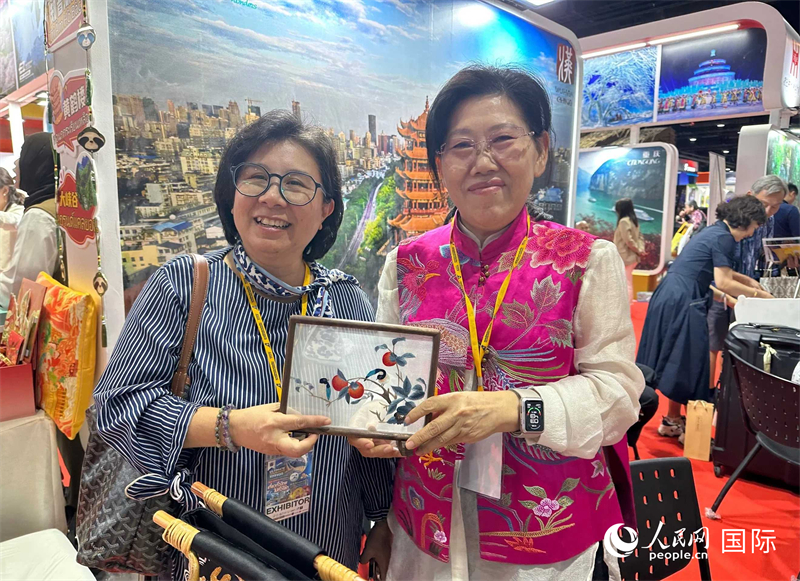 中國“大冶刺繡”傳承人劉小紅（右）參加泰國國際旅游展，向觀眾介紹中國非遺刺繡針法。人民網記者 簡承淵攝